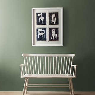 A photograph of different accent chairs hangs in a hallway above a two-person bench.